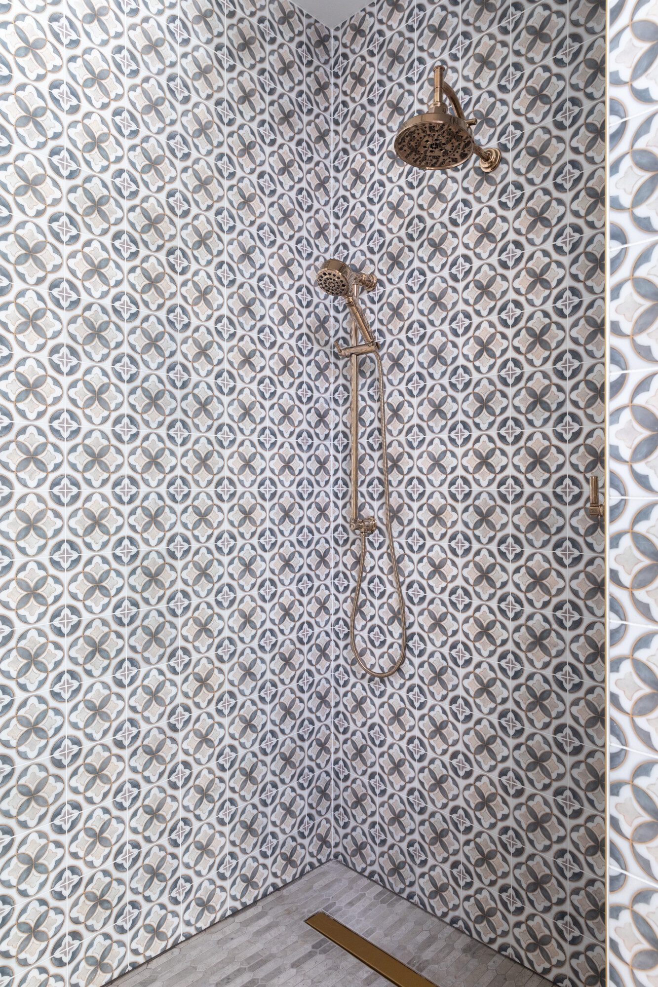 Beautiful shower with patterned tile and gold accents