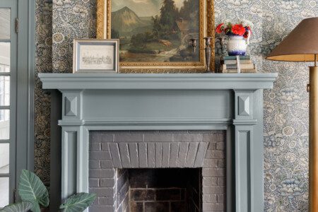 A historic fireplace dressed in traditional wallpaper.