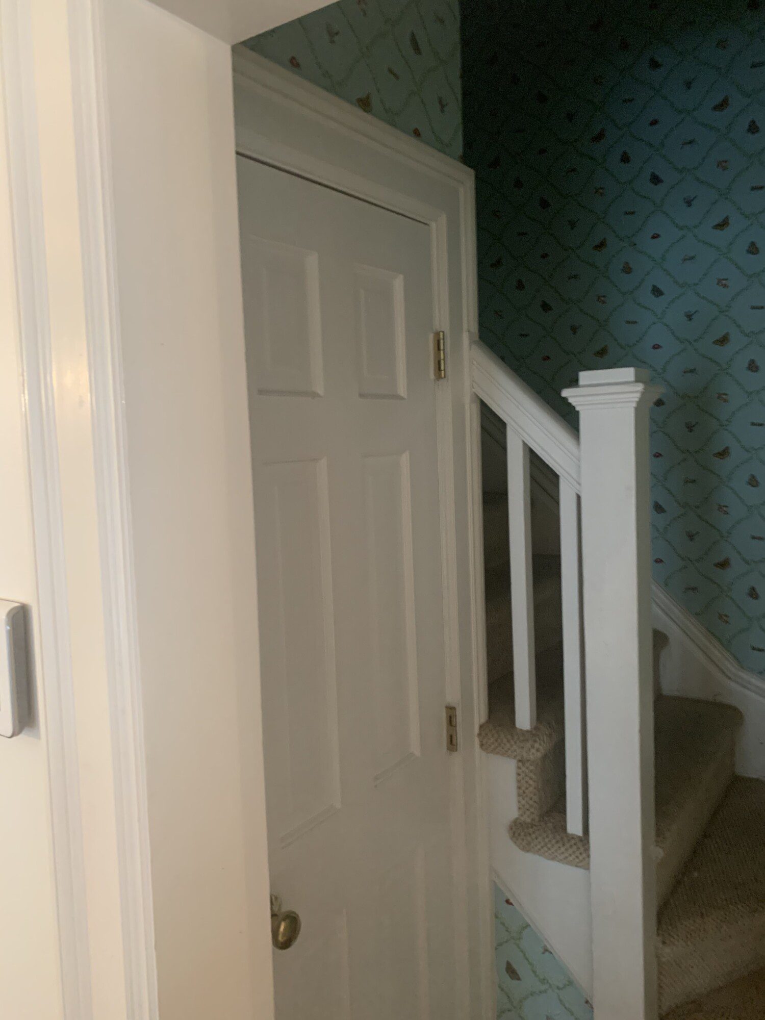 Before photo of staircase with beige carpet and blue pattern wallpaper