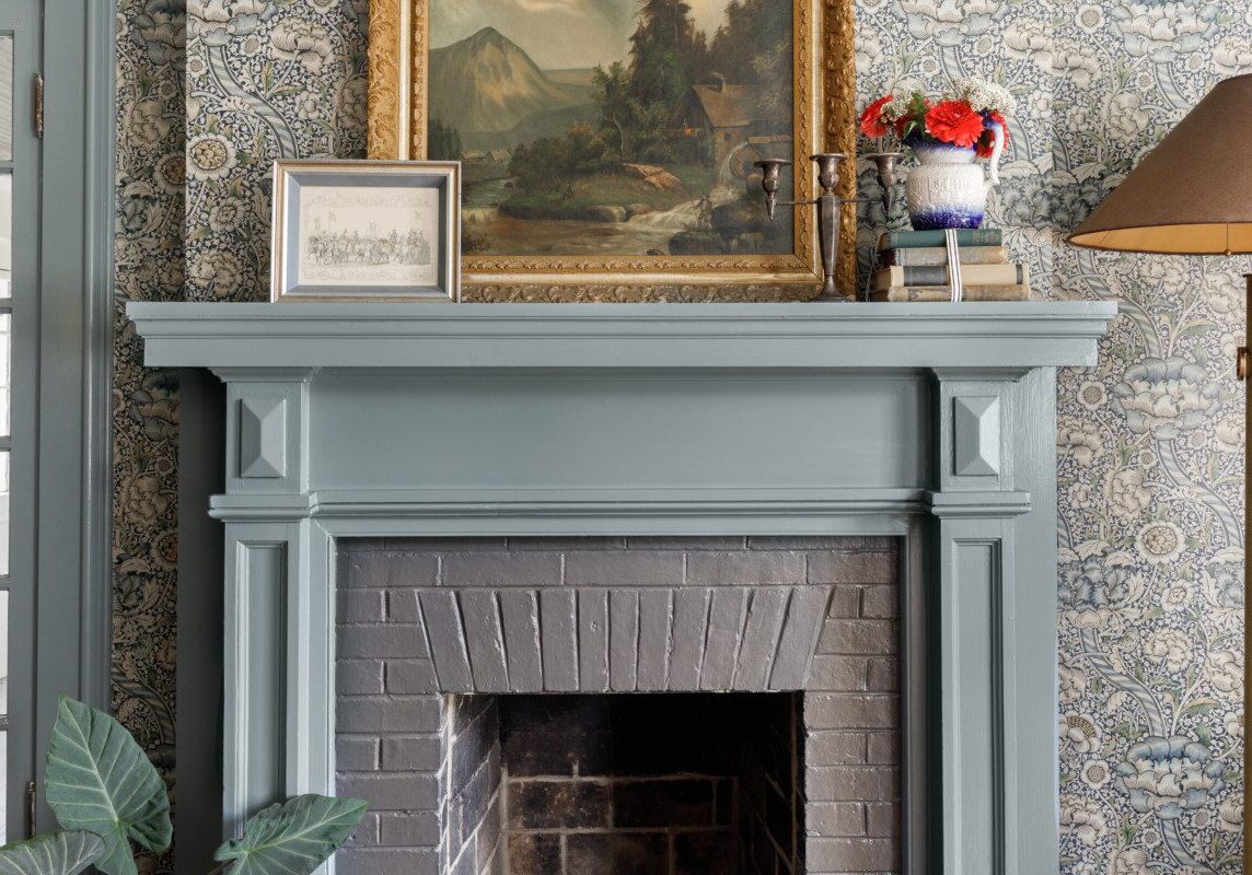 A historic fireplace dressed in traditional wallpaper.