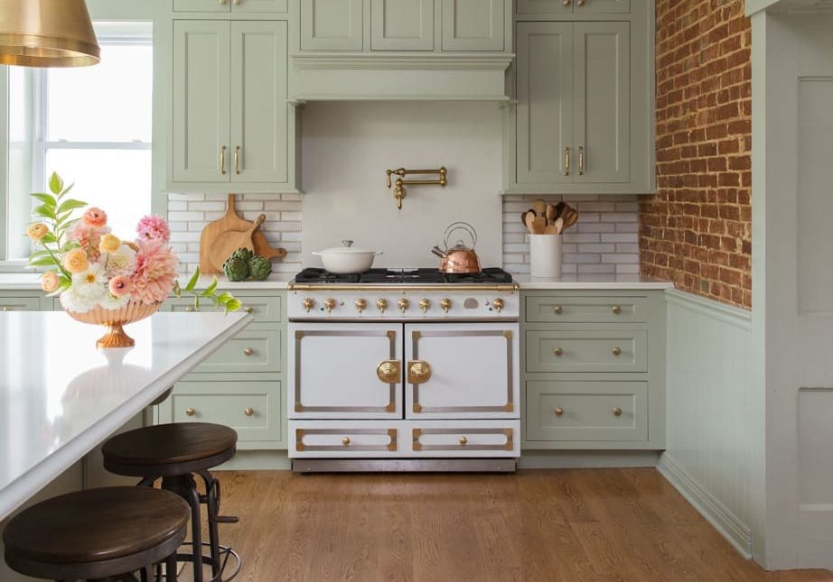bright kitchen with light green cabinetry and gold fixtures