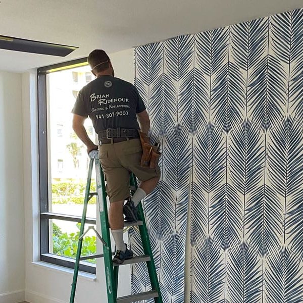 Construction worker installs beautiful blue and white wallpaper