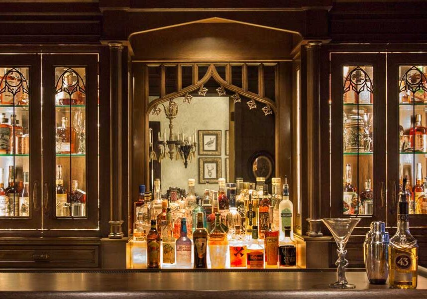 bar-remodel-historic-home-renovation-rausch-afters-secondary Churches erected hundreds of years ago inspired the intricate details. Leaded glass gothic arches in the doors and backlit stained glass in the ceiling speak historically The brass sconces are very old and the drop down TV is very new.