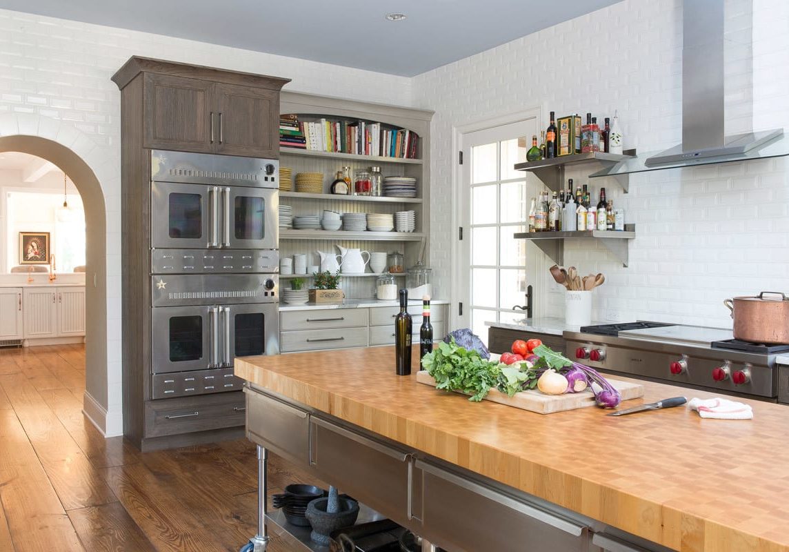 a spacious chef's kitchen with white backsplash and silver appliances